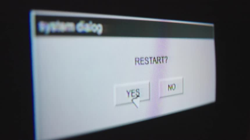 A close-up of a vintage computer screen shows a cursor selecting 'YES' on a 'RESTART?' system dialog box, initiating a system reboot