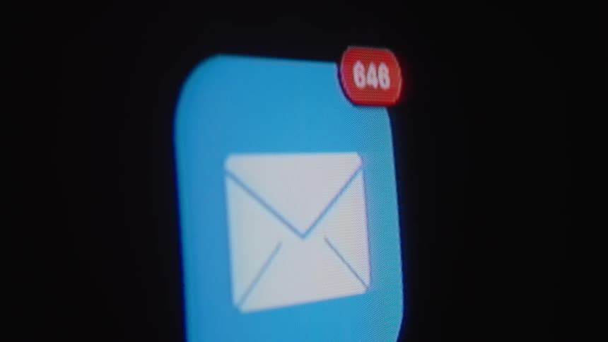 A macro shot of an email app icon on a digital screen with a notification count rapidly climbing into the hundreds
