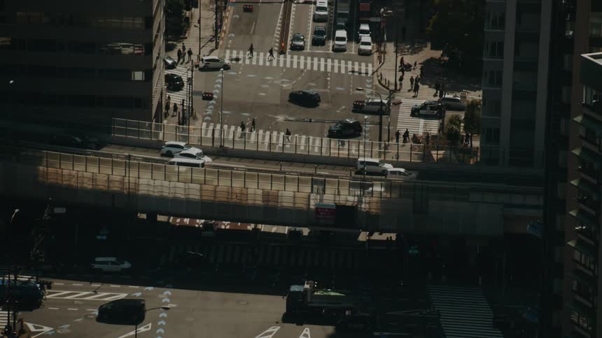 A high-angle view of bustling traffic on a multi-level city intersection on a sunny day