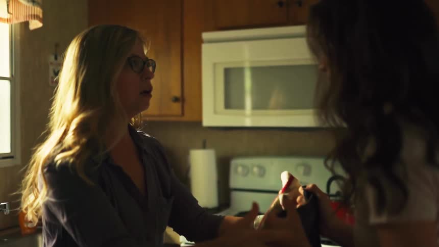A mother and daughter share a joyful and tearful reunion hug in their sunlit kitchen