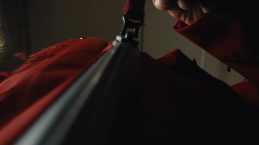 Dramatic low-angle view of a person slowly zipping up a red industrial jumpsuit