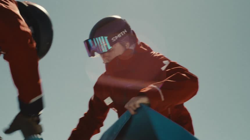 A close-up low angle shot of ski patrol rescuing an injured person and placing them in a sled on a sunny day