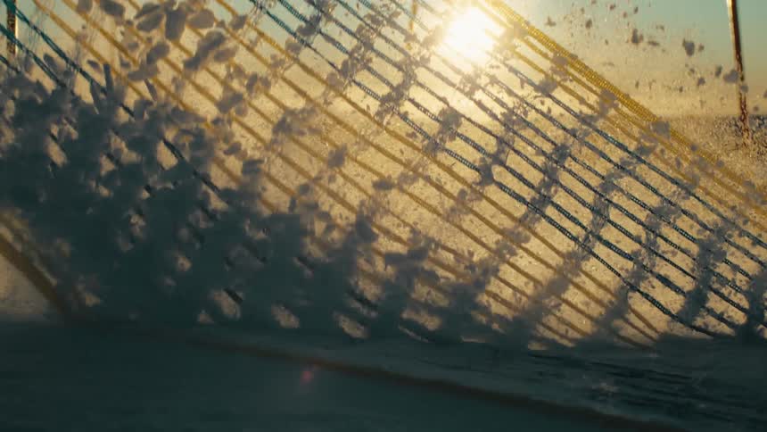 Slow motion of wind blowing snow across a safety net on a mountain slope at sunset