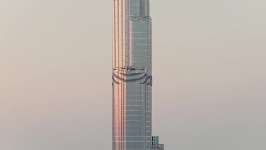 A time-lapse of the sun's reflection moving down the glass facade of the Burj Khalifa skyscraper during a warm sunset