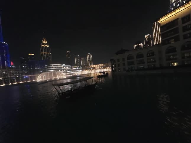 A spectacular nighttime view of the Dubai Fountain and light show, with the illuminated Burj Khalifa and surrounding cityscape