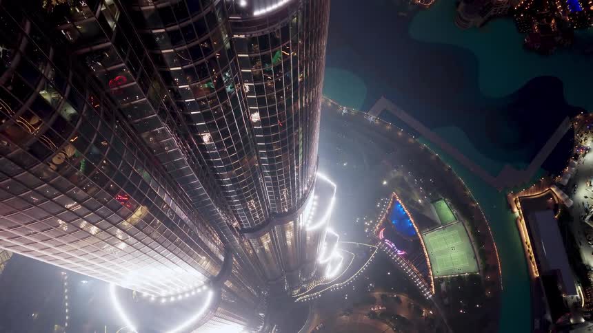 An awe-inspiring vertical view from the top of an iconic skyscraper, looking down at the glittering city lights and waterfront at night