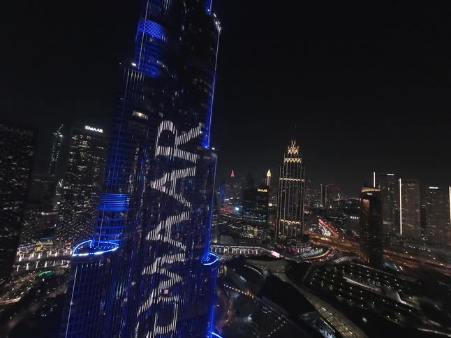 The iconic Burj Khalifa in Dubai displays a spectacular blue and white light show against the glittering city skyline at night