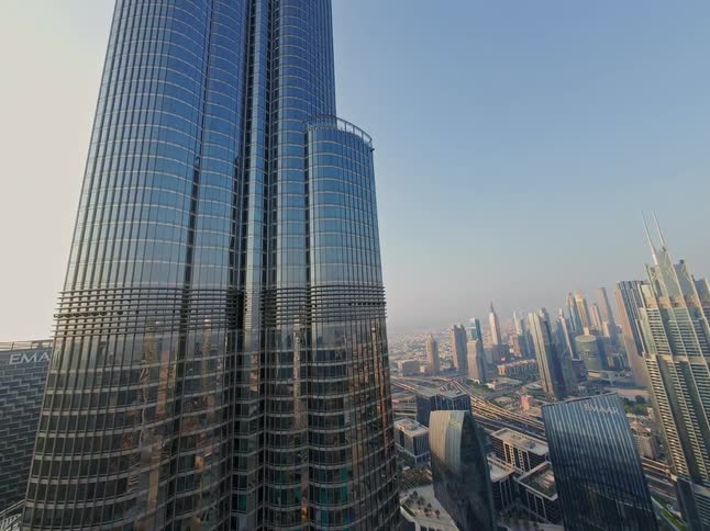 An upward aerial view showcases the magnificent glass facade of the Burj Khalifa against the sprawling urban landscape of Dubai