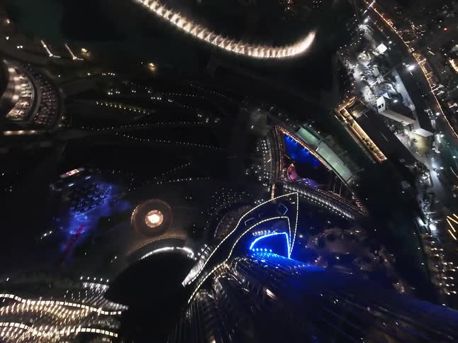 A thrilling FPV drone dive down the illuminated Burj Khalifa at night, revealing the spectacular Dubai Fountain show below