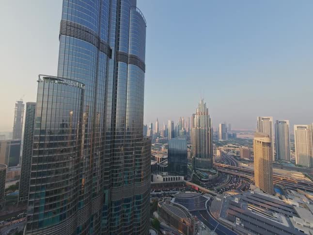 A rising aerial shot captures the impressive scale of the Burj Khalifa and the surrounding modern architecture of downtown Dubai