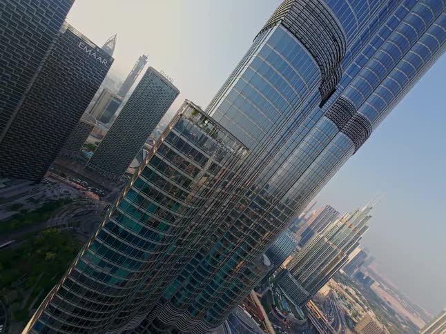 A soaring aerial perspective pans up the glass facade of the Burj Khalifa, tilting to a dramatic top-down view of the Dubai cityscape