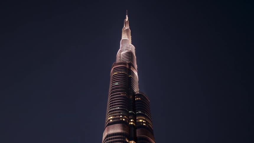 A low-angle view of the iconic Burj Khalifa skyscraper sparkling with a stunning light display against the dark night sky in Dubai