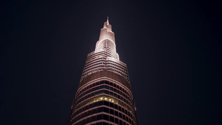 A low-angle view slowly tilts up the illuminated Burj Khalifa skyscraper against the dark night sky in Dubai