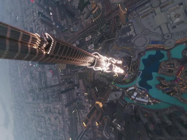 A thrilling FPV drone dives down the iconic Burj Khalifa skyscraper, revealing the dazzling Dubai cityscape at twilight