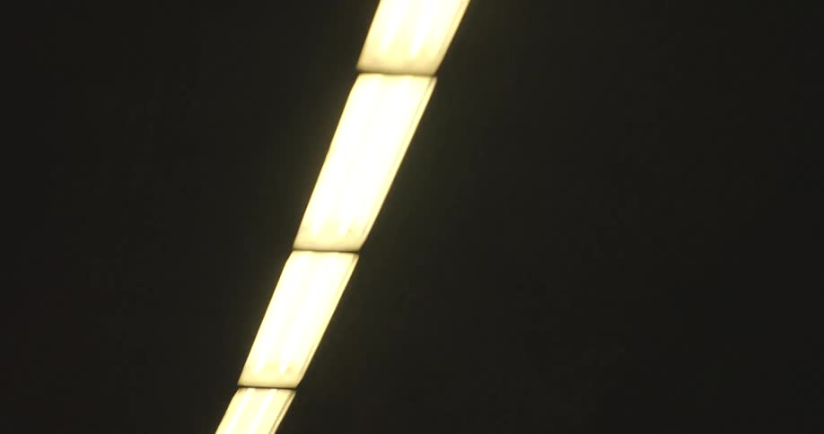A blurry point-of-view shot captures the movement of fluorescent lights on the ceiling of a dark tunnel