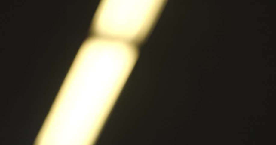 Abstract point-of-view shot of blurry fluorescent lights passing overhead in a dark tunnel