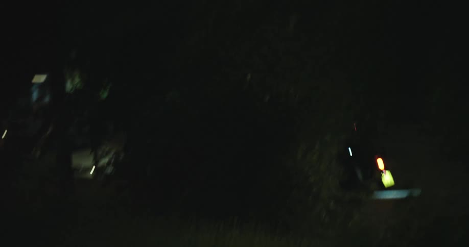 A fast-panning shot transitions from a dark city street to abstract motion-blurred light trails at night