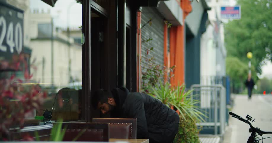 A slow-motion view of a delivery driver picking up a takeout order from a restaurant on a city street