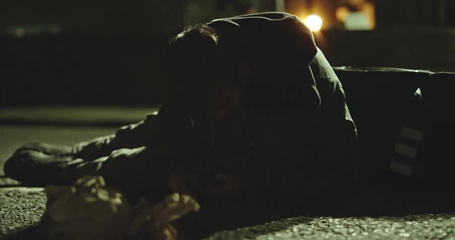 An injured delivery man lies on the street at night after an accident, his bag and food spilled on the ground