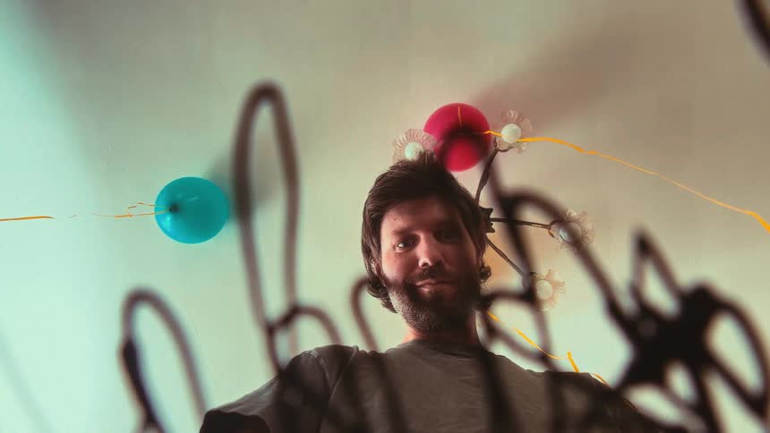 Creative low-angle shot of a smiling artist drawing on a glass surface with a marker