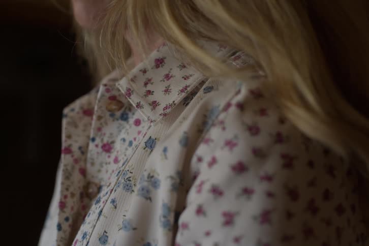 A detailed close-up shot focuses on a woman's floral blouse and her blonde hair
