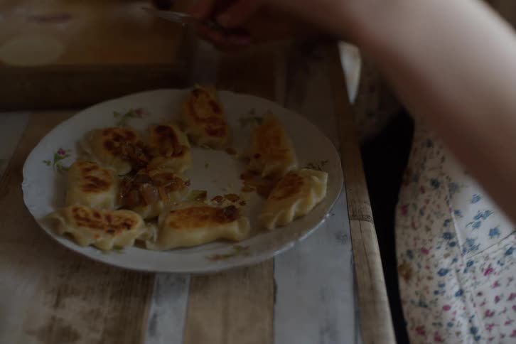 A woman eats freshly made pan-fried pierogi dumplings topped with caramelized onions in slow motion