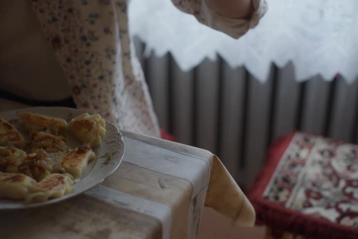 A person eats hot, steaming Ukrainian dumplings, varenyky, with a fork at a table in slow motion