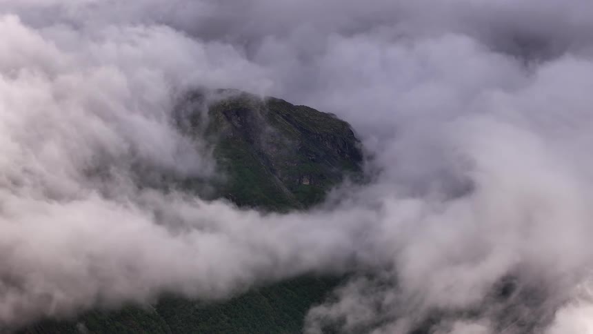 Serene and dramatic view of a mountain peak enveloped in a swirling sea of clouds