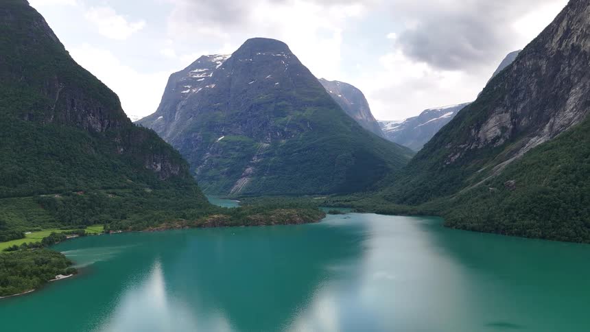 A majestic static aerial view of the turquoise Lovatnet lake nestled between towering green mountains in Norway