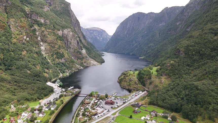 Stunning aerial view of a quaint Norwegian village nestled at the end of a majestic fjord surrounded by towering green mountains