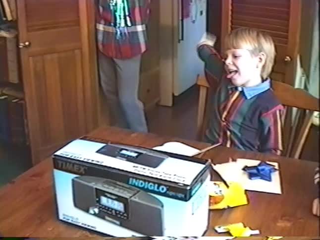 Vintage VHS footage shows an excited young boy celebrating his birthday by waving a wad of cash he received as a gift