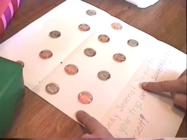 A young boy's hands trace the words on a creative handmade card with coins taped inside as a holiday gift