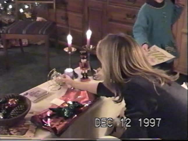 A woman unwraps a glass Christmas gift while a young girl watches in this cozy home video from December 1997