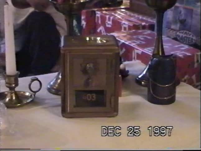 A vintage post office box piggy bank sits on a table with other Christmas decorations in this 1997 home video