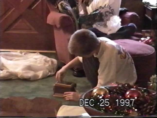 A young boy excitedly opens a wooden music box on Christmas morning in a nostalgic home video from 1997