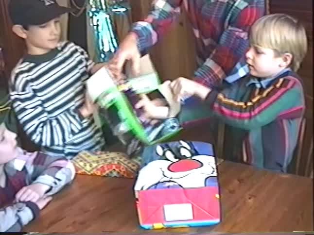 Vintage VHS footage of young boys excitedly unwrapping a birthday gift together at a party in the 90s
