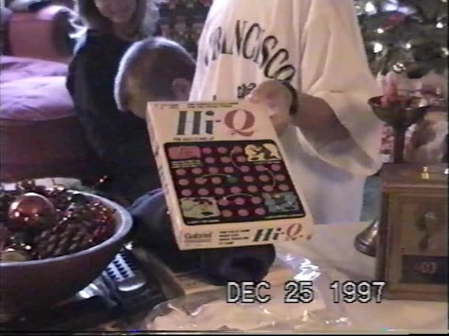 A young boy holds up his new 'Hi-Q' board game on Christmas morning in 1997