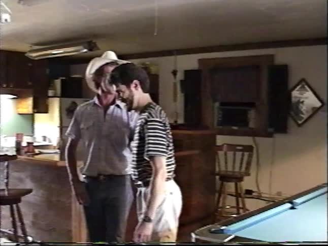 Vintage home video footage shows two men having a conversation in a game room with a pool table