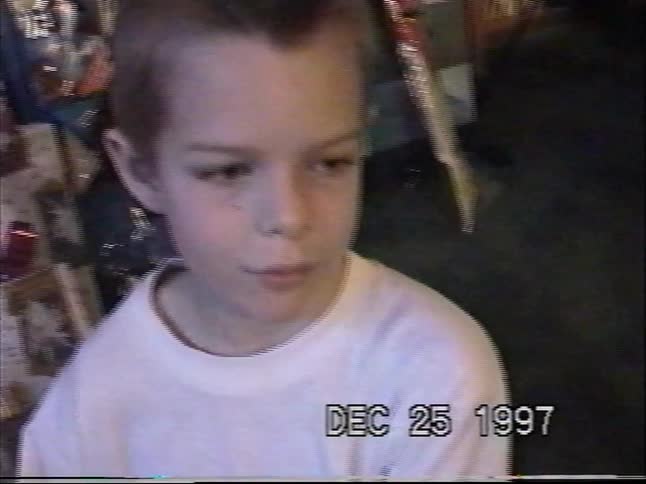 Boy checks out a new wristwatch beside Christmas gifts in a 1997 home video