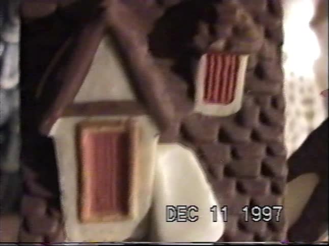 A shaky VHS home video from 1997 gives a tour of a charming 'Dickens' Village' Christmas decoration set with miniature houses and figurines