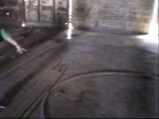 A young boy explores a dark, abandoned industrial building with old tracks on the floor, revealing a mysterious bubbling pit
