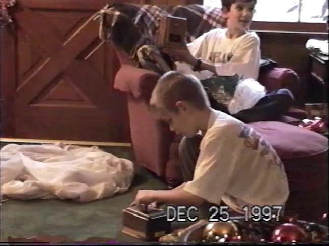 Vintage home movie from Christmas 1997 shows two young boys opening their presents in the living room