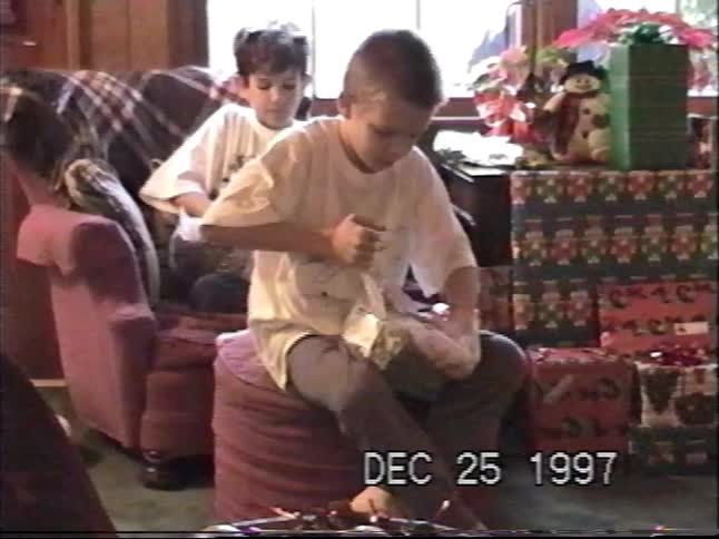 Two young brothers open their Christmas stockings in the living room on Christmas morning in 1997