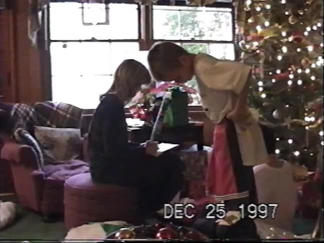 A vintage VHS home video from 1997 shows a family opening presents together on Christmas morning in their living room