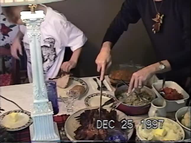 Vintage VHS footage from 1997 shows a woman carving a holiday roast at the dinner table on Christmas day
