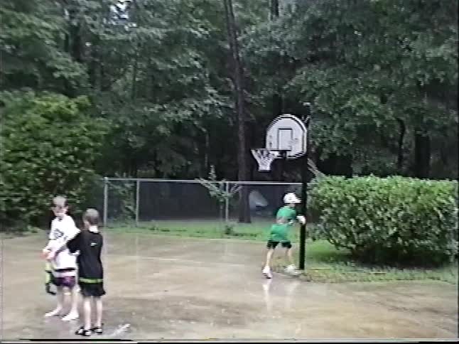 Vintage footage shows a group of boys playing football in the rain, culminating in a successful trick shot into a basketball hoop