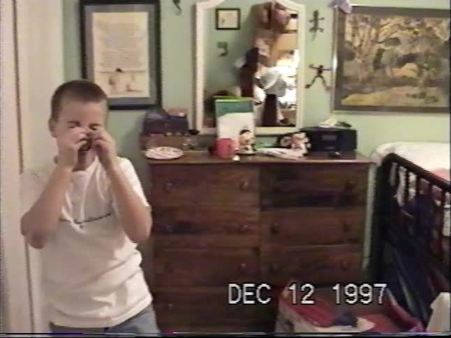 Two young boys laugh hysterically and make goofy faces at the camera in their bedroom in a 1997 home video