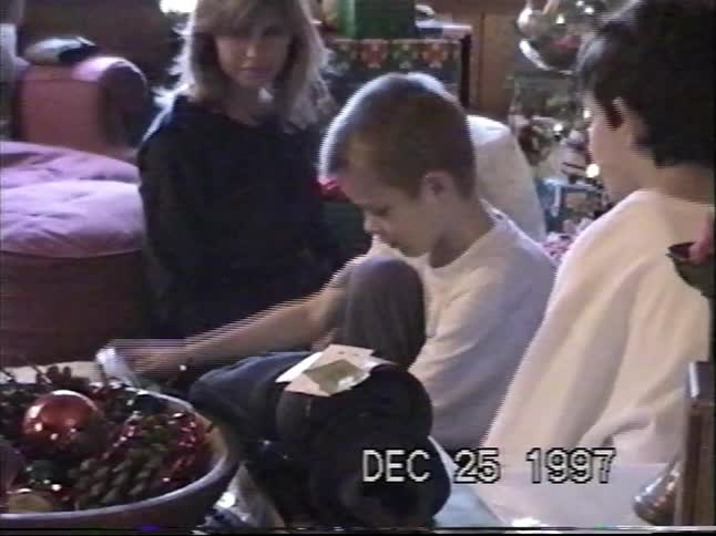 Children happily open presents around the Christmas tree on a nostalgic Christmas morning in 1997, captured on home video
