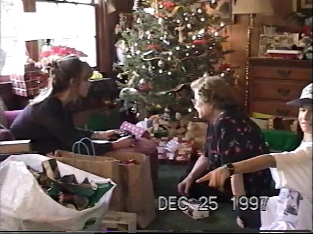 A family opens presents together around the Christmas tree on Christmas morning in this 1997 home video