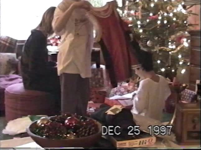 Three siblings gather around the Christmas tree to open their presents on Christmas morning in 1997